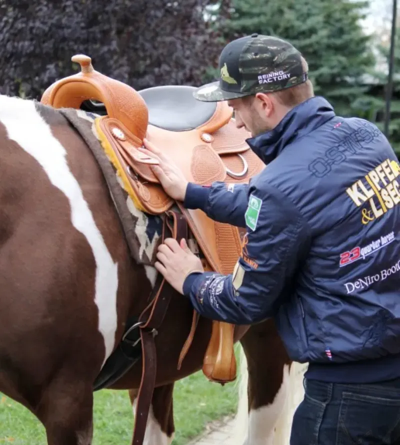 Sattler passt einen Westernsattel am Pferd an