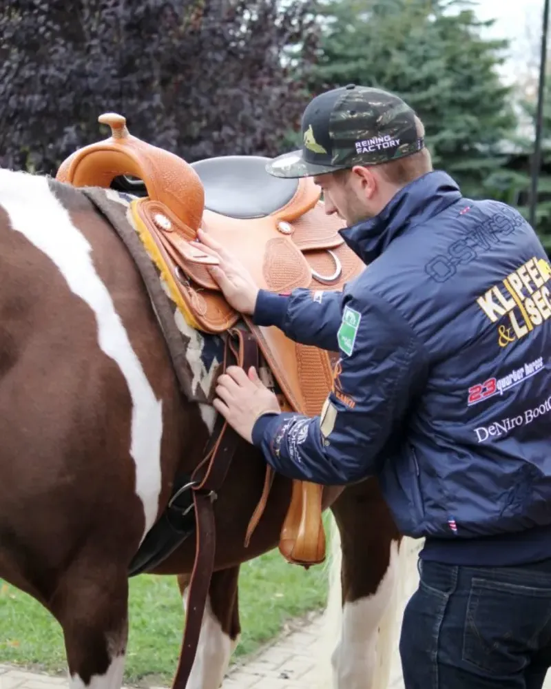 Sattler passt einen Westernsattel am Pferd an